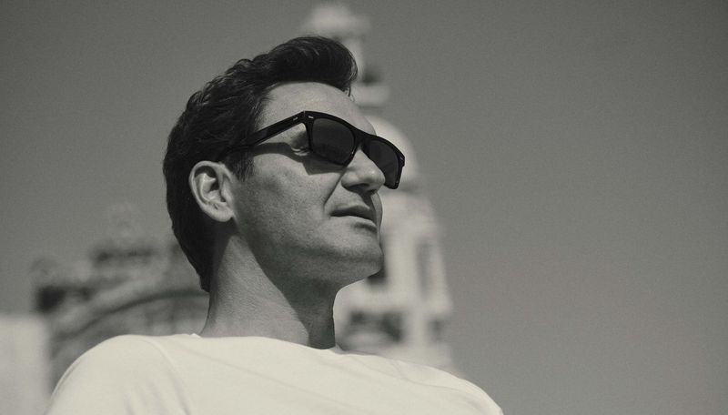 Roger Federer wearing black sunglasses and a white t-shirt in a black and white portrait photographed by Gregory Harris for Oliver Peoples.