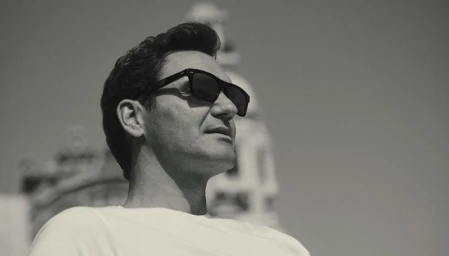 Roger Federer wearing black sunglasses and a white t-shirt in a black and white portrait photographed by Gregory Harris for Oliver Peoples.