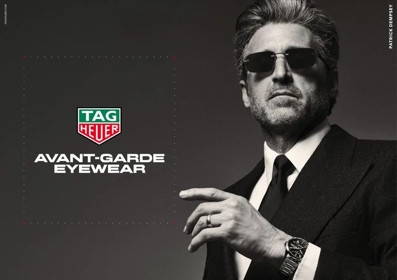 Patrick Dempsey wearing dark sunglasses, a tailored black suit, and a wristwatch in a TAG Heuer campaign.