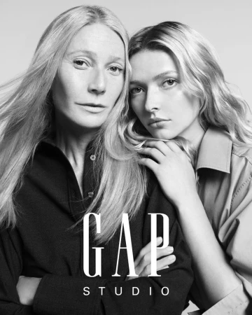 A black and white portrait of two women, one fair-skinned with long blonde hair, the other slightly behind with blonde hair, in a studio setting.