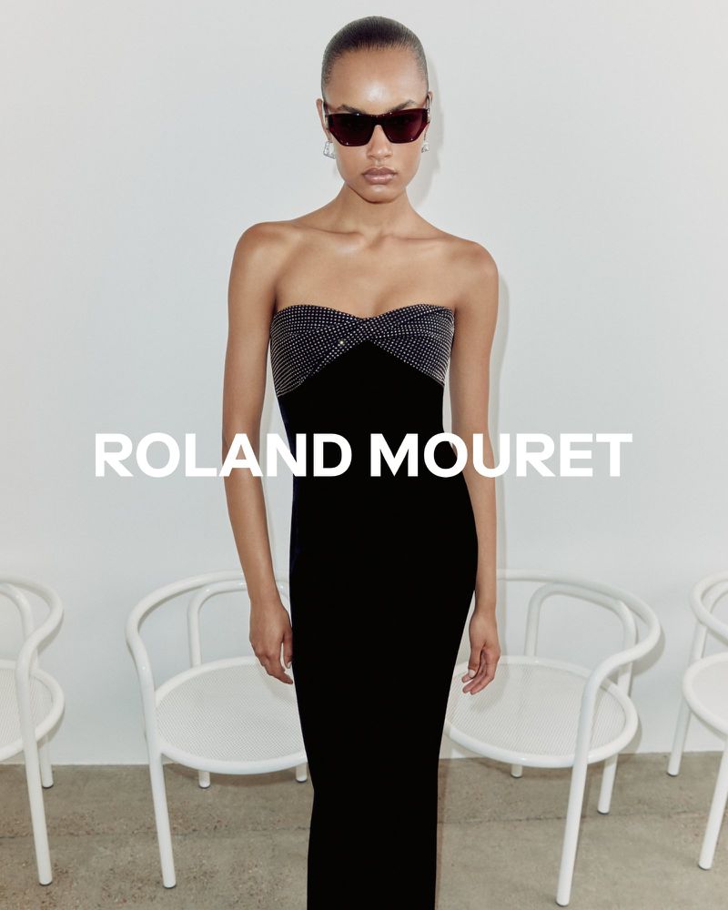 Elegant adult woman in black strapless evening gown and sunglasses posing in bright studio setting. Fashion editorial photoshoot.