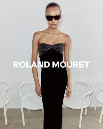 Elegant adult woman in black strapless evening gown and sunglasses posing in bright studio setting. Fashion editorial photoshoot.