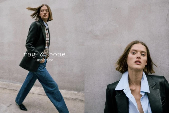 Fashion advertisement featuring a female model wearing a blazer, shirt, and jeans, posing in front of a grey wall, brand logo visible.