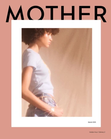 Fashion editorial shot of a young adult female model with curly hair, wearing a light blue top and jeans, on a peach background.
