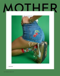 Close-up of model wearing denim cut-off shorts with an embroidered cherry patch, sheer socks, and sneakers against a green backdrop.