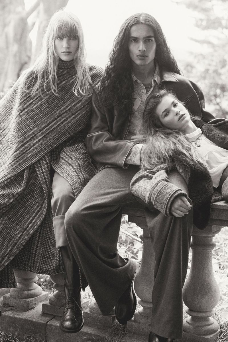 Three models pose in an outdoor setting, showcasing fall fashion with tweed, dark coats, and trousers in a black and white editorial shot.