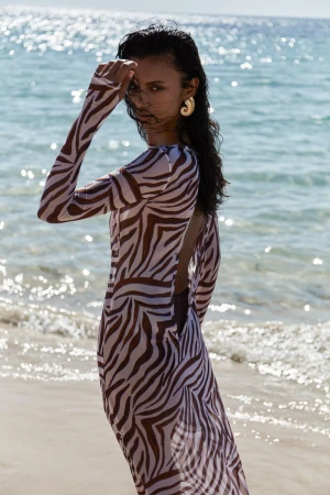 Model Madhulika Sharma poses on a sunny beach wearing a zebra-print long-sleeved sheer dress with an open back.