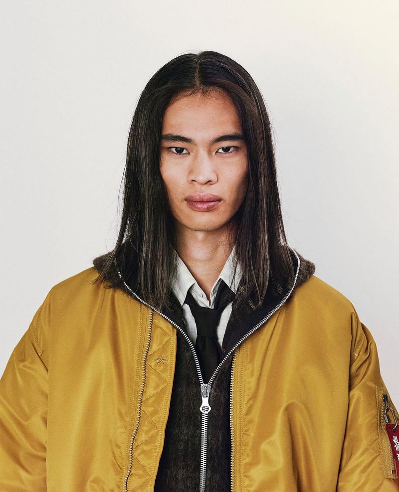 Model with long dark hair wearing a mustard yellow bomber jacket against a plain white background for Alpha Industries Japan
