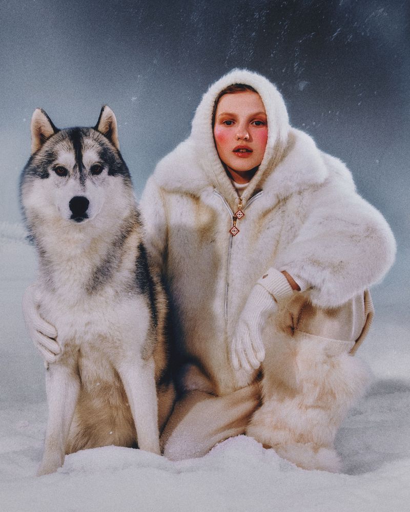 Woman and Husky dog posing in snowy environment wearing winter fashion. They are looking forward with a serene expression.