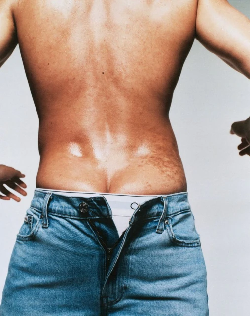 Male torso with open denim jeans and underwear, showcasing an intimate fashion portrait in a bright setting with visible skin details.