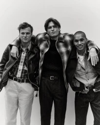 Three male models with arms around each other in casual menswear against a white seamless background for J. Crew
