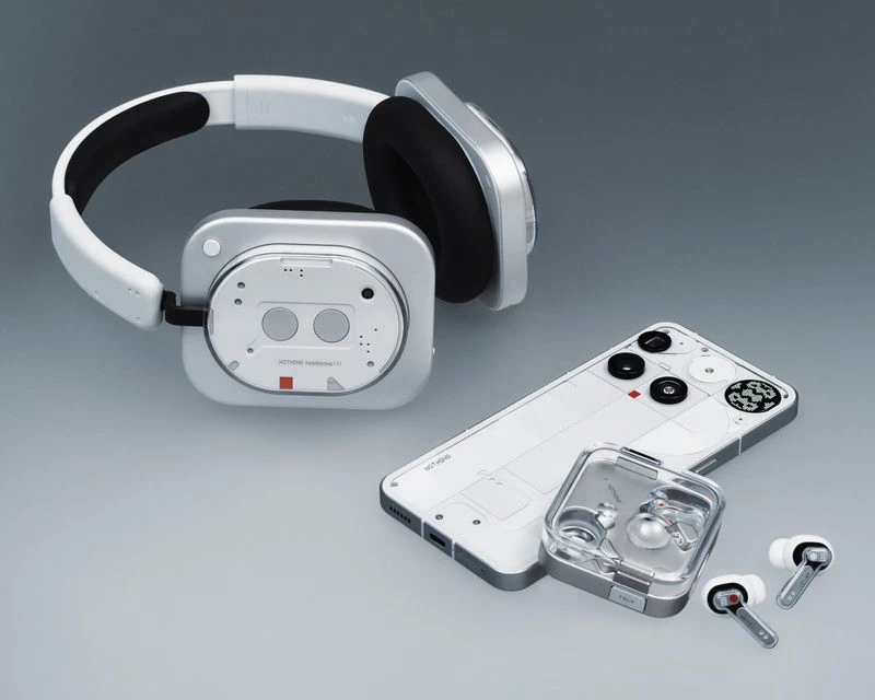 Studio shot of wireless headphones, wireless earbuds in a case, and a smartphone on a gray background, emphasizing their design.