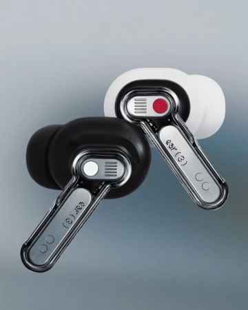 Close-up studio shot of a pair of sleek, modern wireless earbuds with a transparent stem, one black and one white, against gray backdrop.