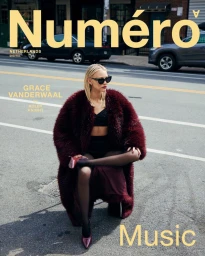 Grace VanderWaal seated on a city street wearing a burgundy faux fur coat, black top, and sunglasses for Numero Netherlands.