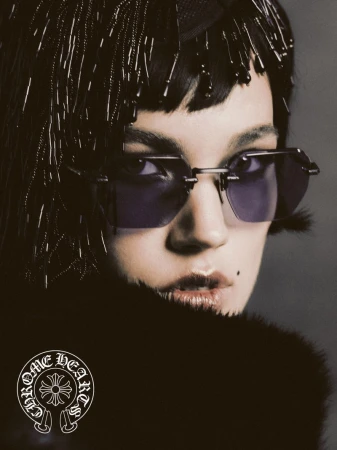 Close-up portrait of a fashion model wearing sunglasses and a beaded headpiece, showcasing dark fur clothing and Chrome Hearts logo.