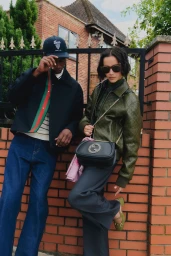 Two fashion models posing by a brick wall and gate in designer outerwear and denim for FLANNELS AW25 Autumn Comforts.