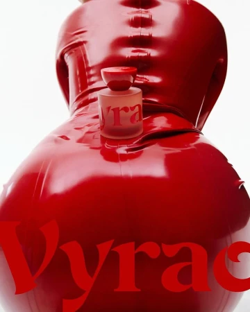 Red latex-clad figure presents a perfume bottle with 'Vyrao' text, set against a stark white background in a beauty and fashion context.