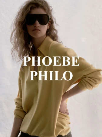 Fashion editorial shot of a woman posing in sunglasses and a yellow shirt against a white backdrop, showcasing modern style and design.
