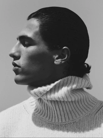 Portrait of a young adult man in profile, wearing a knitted turtleneck sweater, showcasing fashion and style in a studio setting.