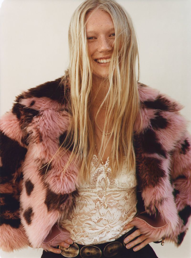 Model Evelina Lauren smiling in a pink and brown faux fur jacket with a lace camisole against a light background.