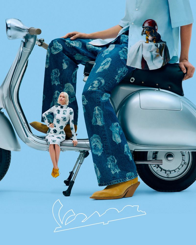Stylish person seated on a vintage silver Vespa scooter, adorned with dog-themed patterns, complemented by a miniature model.