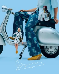 Surreal fashion composition with a model seated on a silver Vespa scooter beside a miniature model against a light blue backdrop.