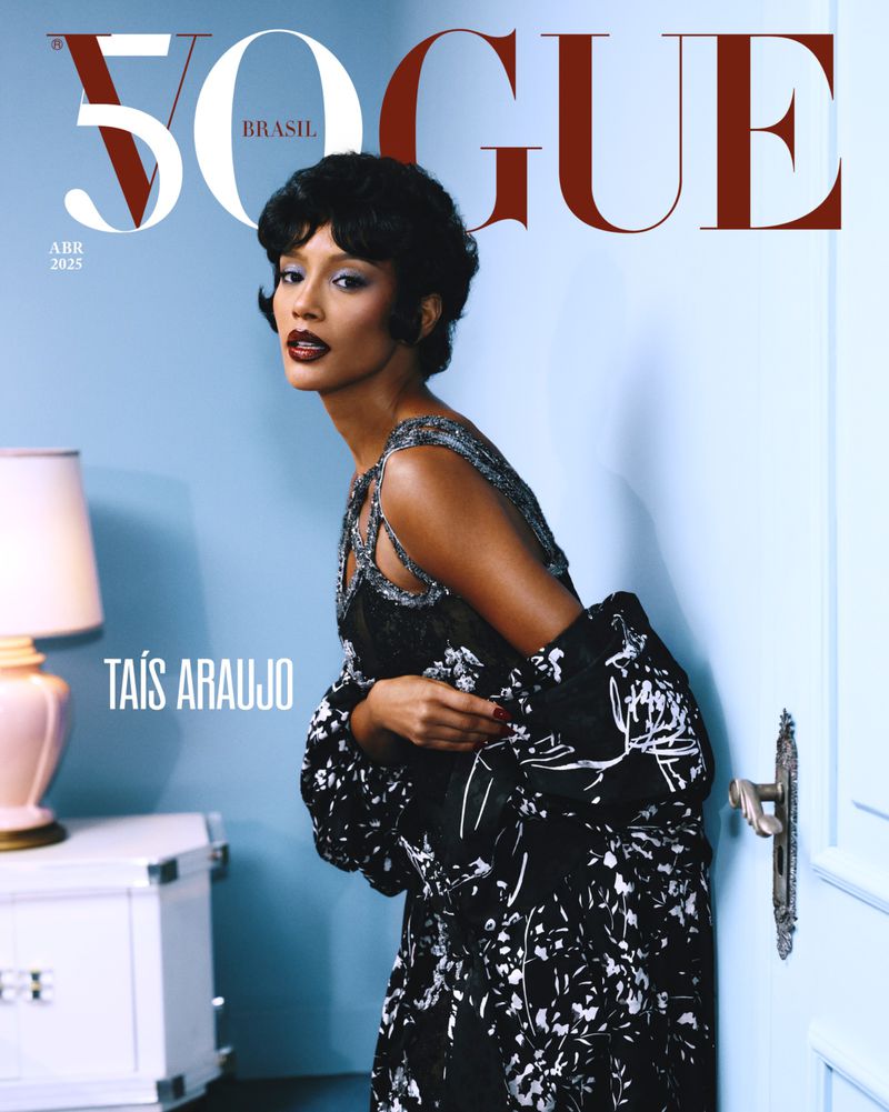 Vogue Brasil cover featuring Taís Araujo in a floral dress and short black hair, posing next to a pale blue wall and vintage-style props.
