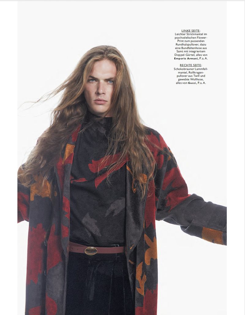 Long-haired male model wearing a patterned red and black coat against a bright white background for Monsieur Magazin Germany