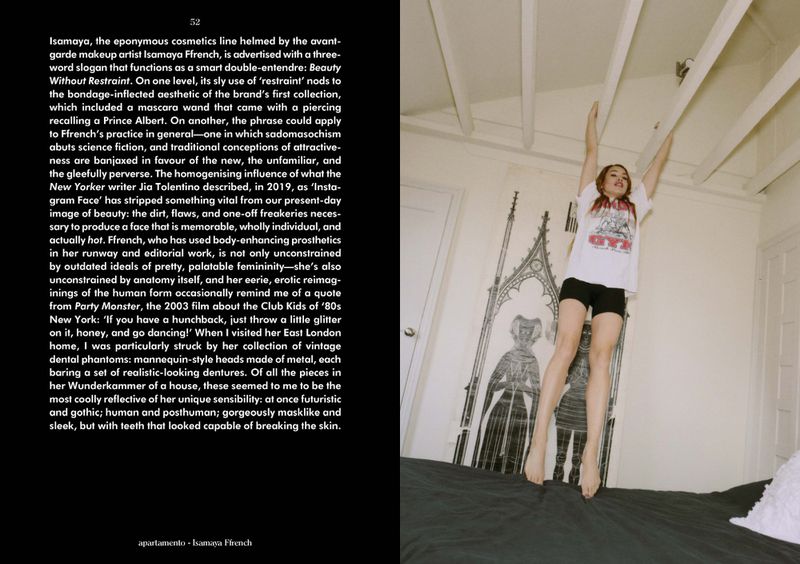 Woman with red hair jumps barefoot on a bed in a bedroom with a gothic-style poster on the wall, white ceiling, and black sheets.