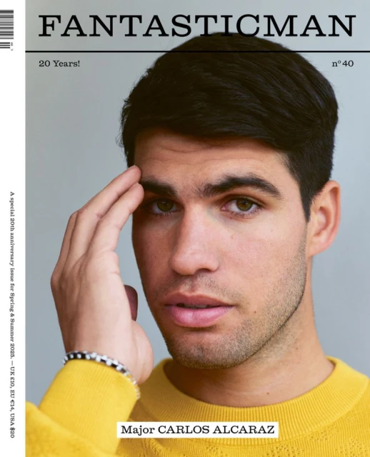 Close-up portrait of Major Carlos Alcaraz on a magazine cover. He wears a yellow sweater, with his hand near his forehead.