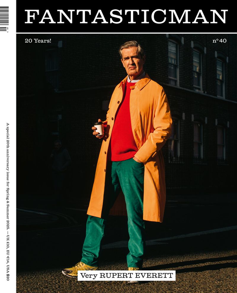 Middle-aged man in orange coat holding coffee cup in urban setting for Fantastic Man magazine cover, celebrating 20 years.