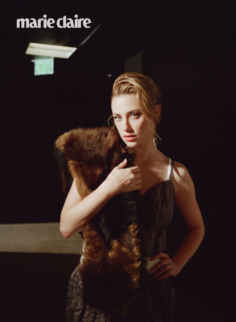 Blonde woman posing in a low-lit indoor setting with a fur stole, wearing a patterned dress, shot for Marie Claire magazine.