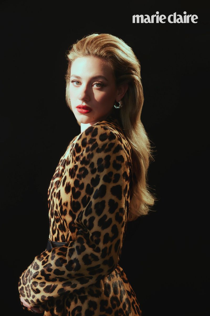 Attractive blond woman in an animal-print dress poses in a beauty shot for Marie Claire magazine against a solid black backdrop.