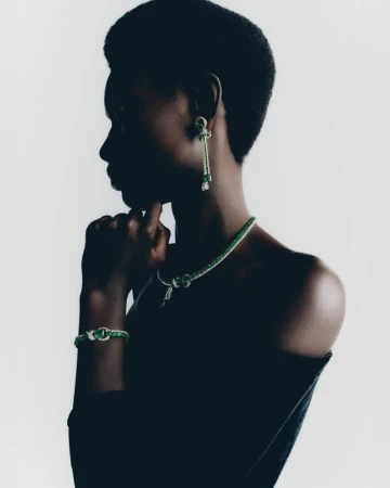 Woman in profile wearing matching jewelry set of necklace, bracelet and earrings. She is fair-skinned with dark hair and dark clothes.