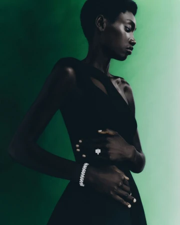 Elegant portrait of a Black woman in a black dress wearing diamond jewelry against a gradient green background, showcasing fashion and beauty.