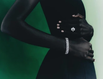 Close-up of a model wearing a diamond ring and tennis bracelet against a gradient green background for Harrods.