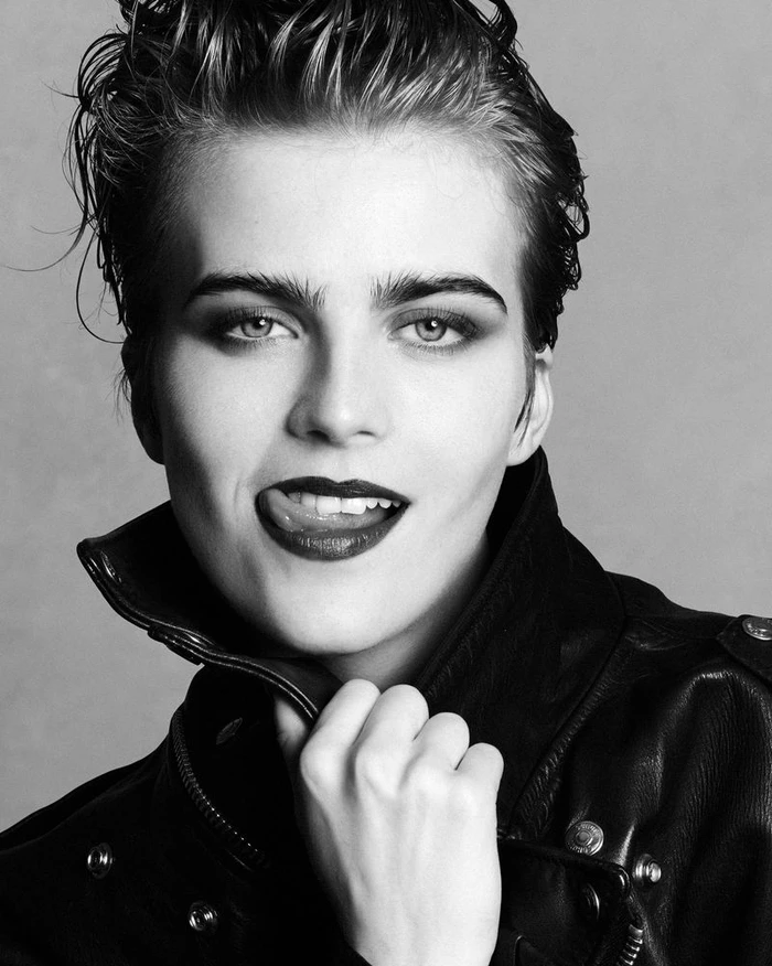 Close-up portrait of model Libby Bennett wearing a black leather jacket against a grey seamless background