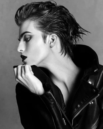 Monochrome portrait of model Libby Bennett in a black leather jacket with dark slicked-back hair against a grey backdrop