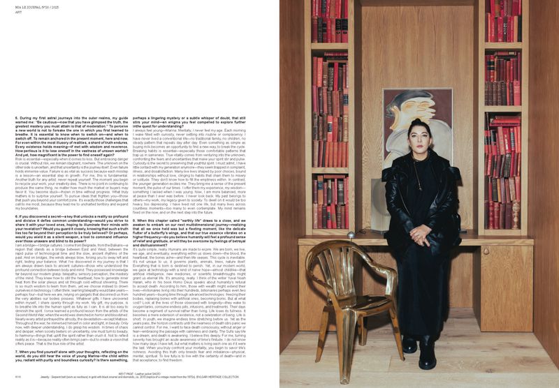 Woman in a black outfit poses in front of a wooden shelf filled with books and a painting in an indoor setting with a gold chair.