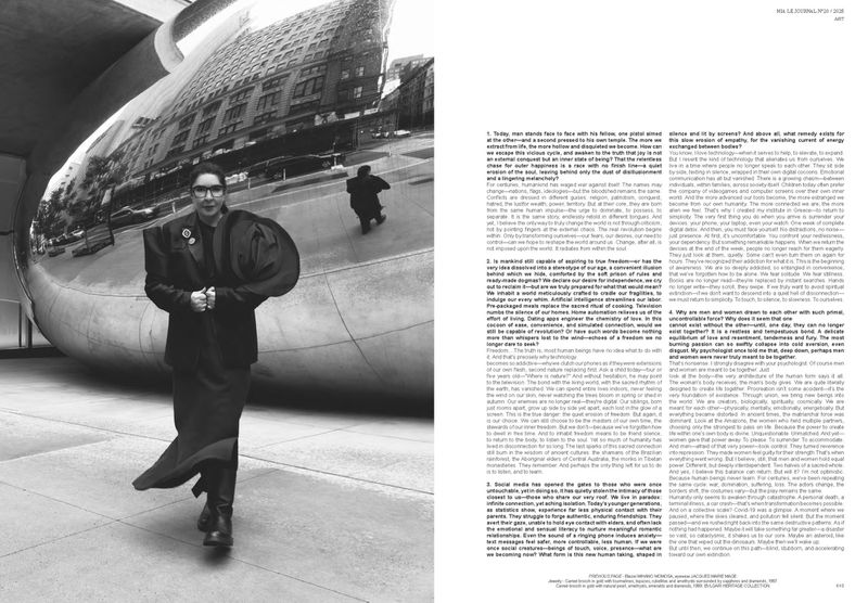 A person in a dark coat walks in front of a large, reflective sculpture in an outdoor setting, with buildings reflected on the sculpture.