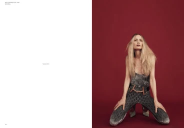 Model Georgina Grenville kneeling against a deep red background for Mia Le Journal