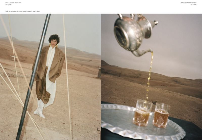 Editorial fashion shot of a woman in a brown suit in a desert landscape with beverage service featuring a teapot and glasses.