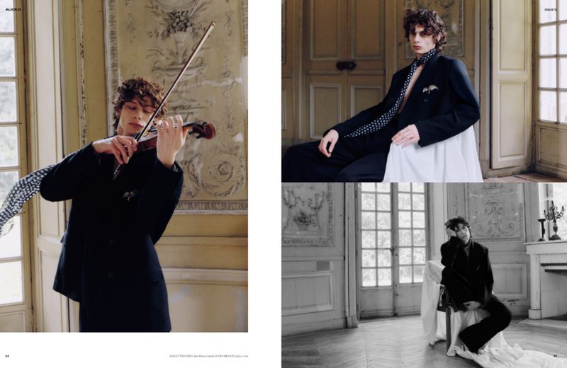 Male fashion model playing violin in an ornate room, dressed in a black suit and tie, with black and white photography and classic details.