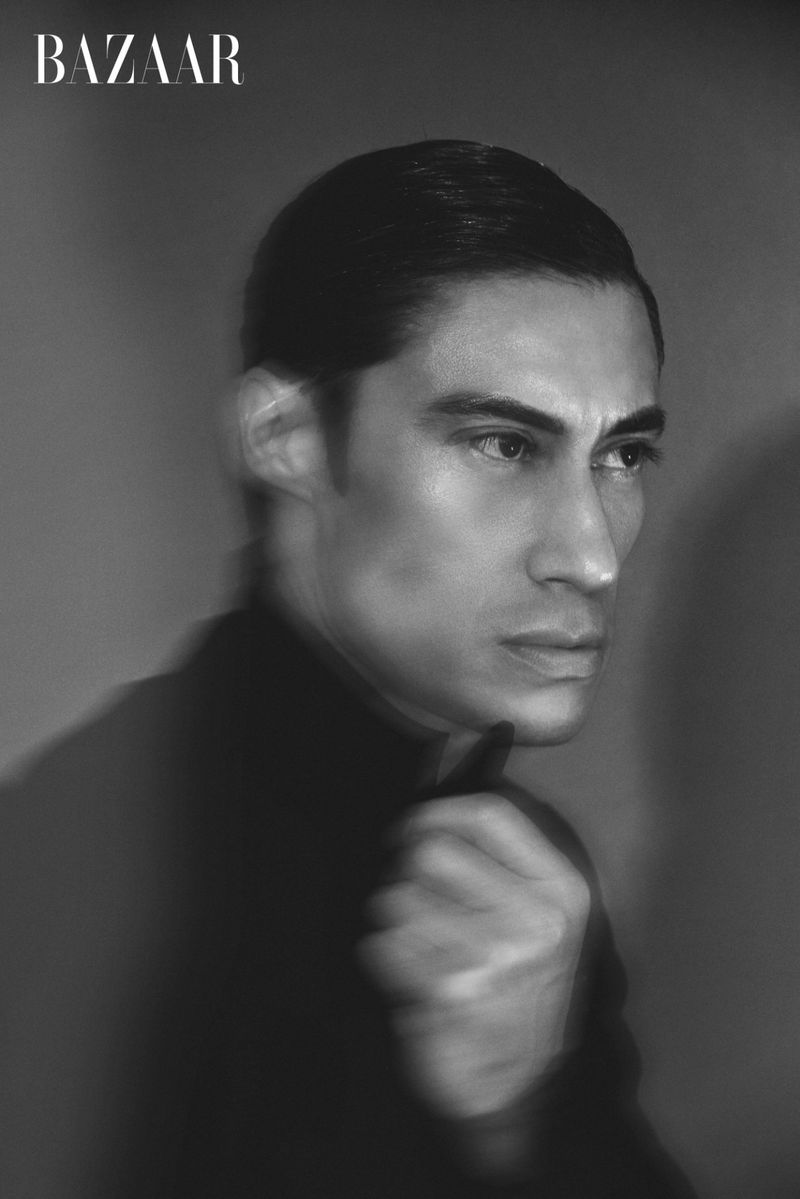 Monochrome portrait of a stylish adult male looking to the side against a gray background, captured in a classic studio setting.