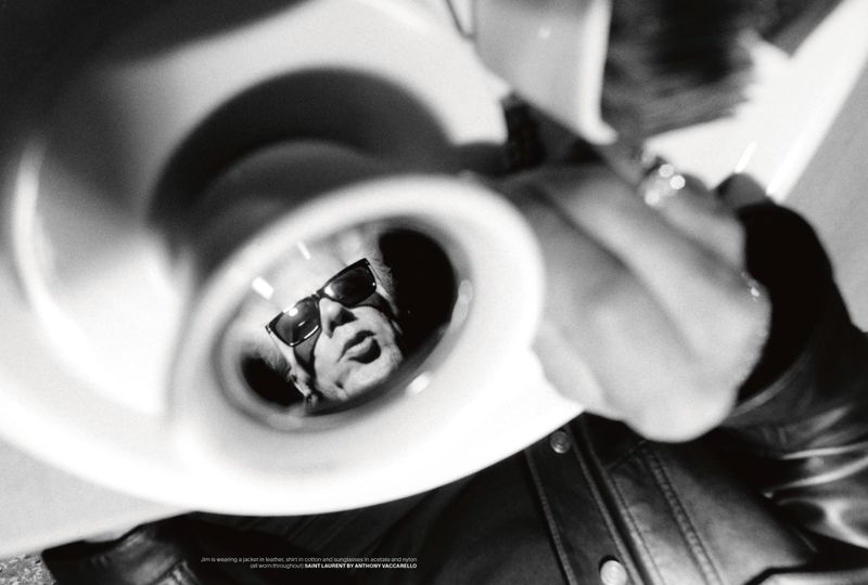 Jim Jarmusch reflected inside a white ceramic cup held by a person in a leather jacket