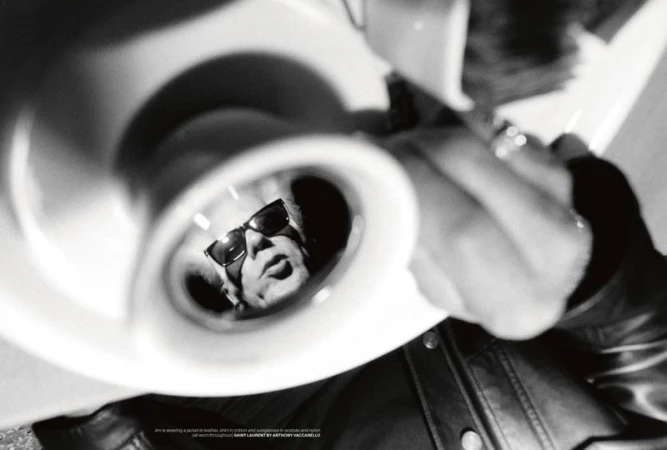 Jim Jarmusch reflected inside a white ceramic cup held by a person in a leather jacket