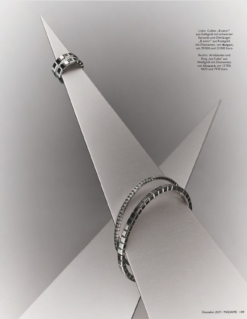 Elevated view of metal rings with square stone accents, presented on pointed white stands in a monochromatic product-style shot.