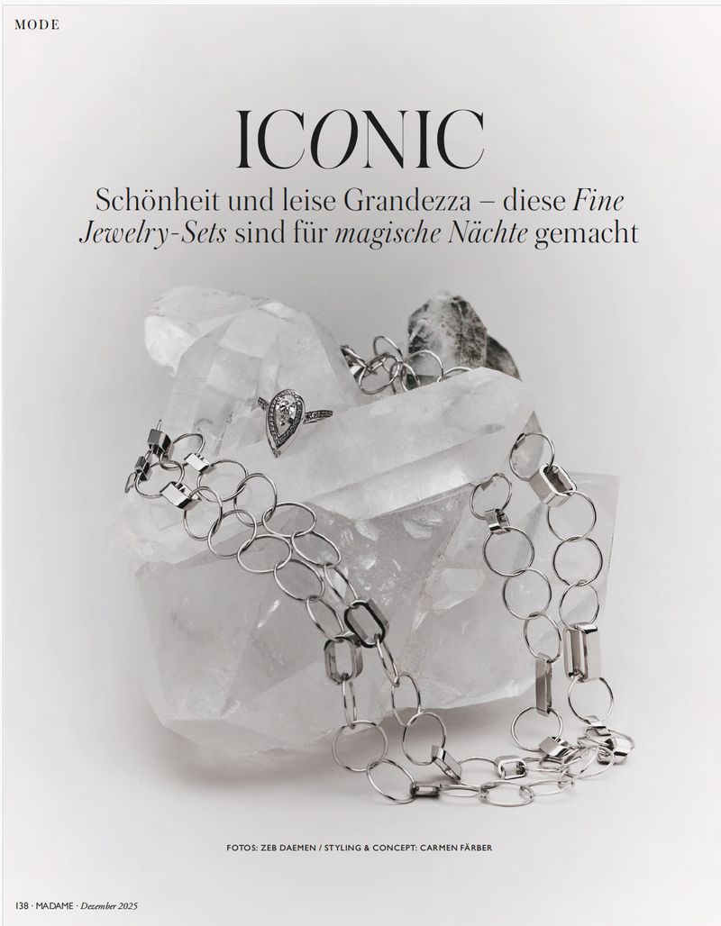 Elegant jewelry displayed on a translucent crystal, featuring a silver ring and chain necklace on a clean, bright white background.