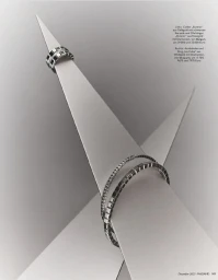 Diamond and gold rings and geometric bangles displayed on sharp triangular sculptural paper forms against a soft grey backdrop.