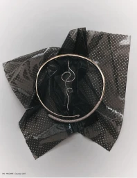 Gold circular collar necklace with pavé diamond detailing and a serpentine diamond drop pendant on sheer black polka-dot fabric.